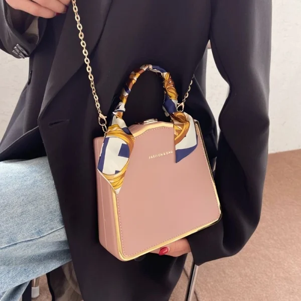 Luxury women’s box handbag made of PU leather with scarf-wrapped handle for daily fashion use in pink outfit