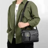 “Men's leather shoulder bag made of PU leather with multi-pocket design for business and travel use in black outfit.”